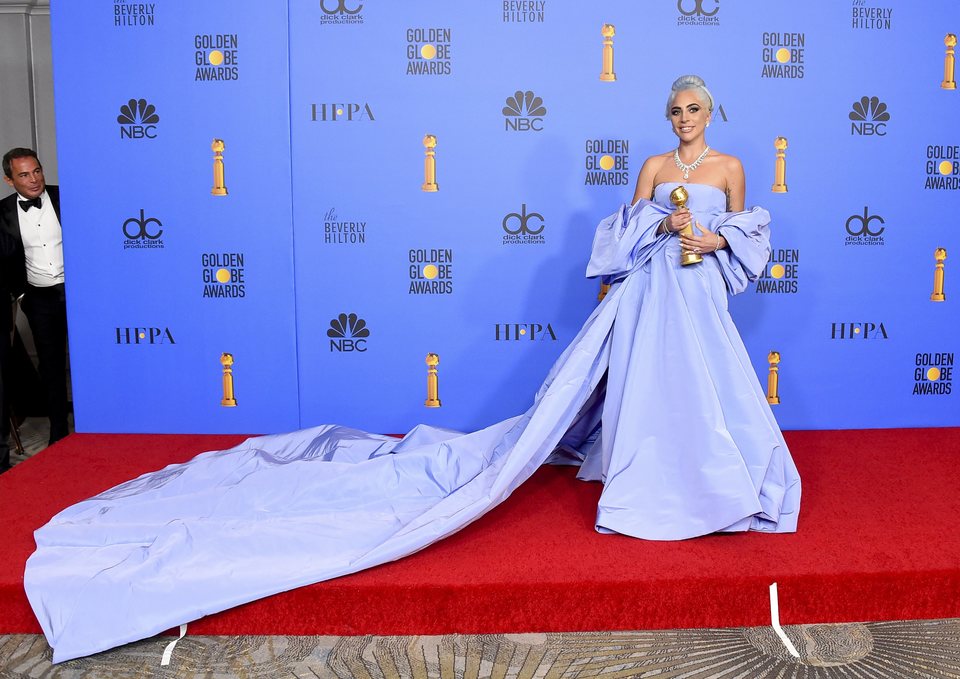 Lady Gaga posing with the Golden Globe for Best Original Song
